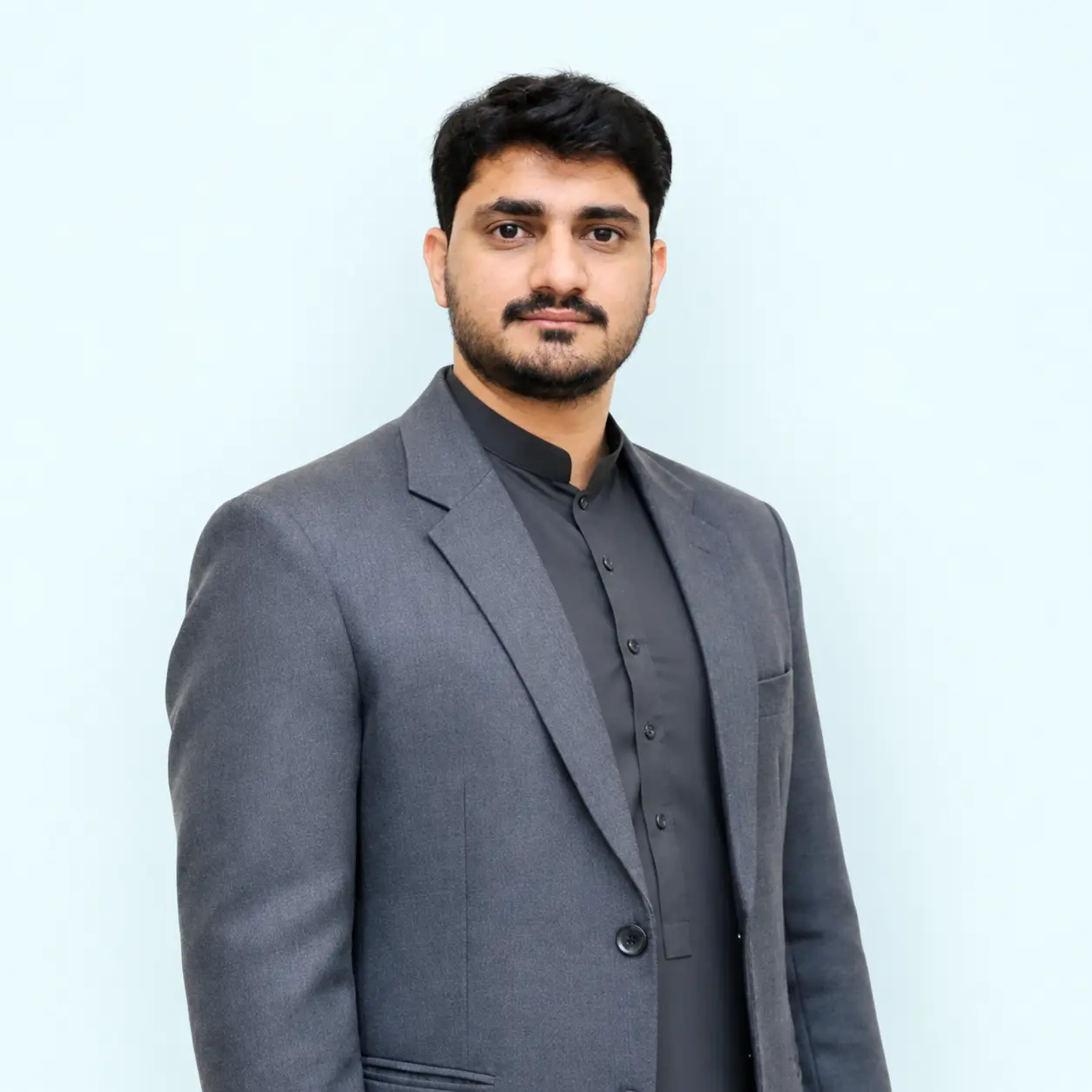Amplivus founder wearing a grey blazer against a soft light blue background.