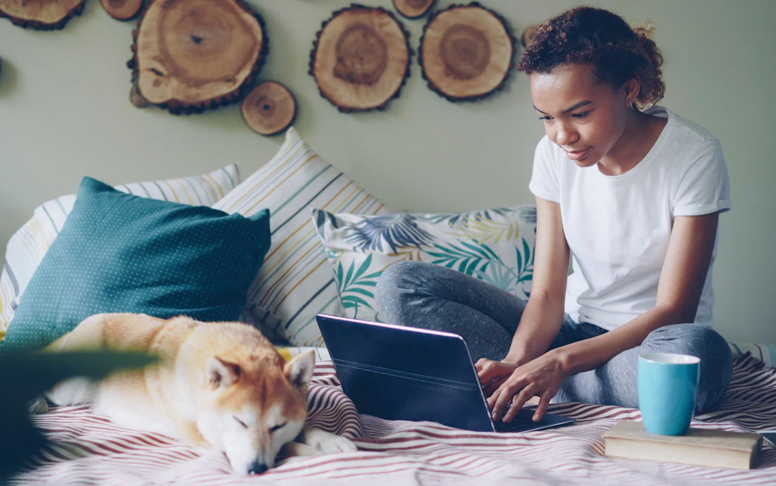 Pet brand owner working on a laptop with her dog beside her