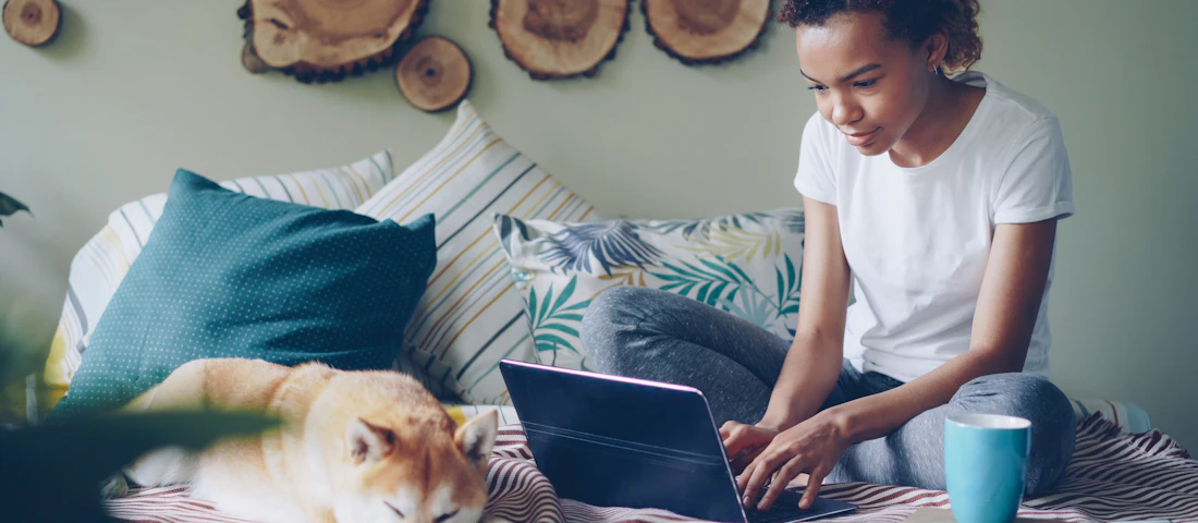 Pet brand owner working on a laptop with her dog beside her